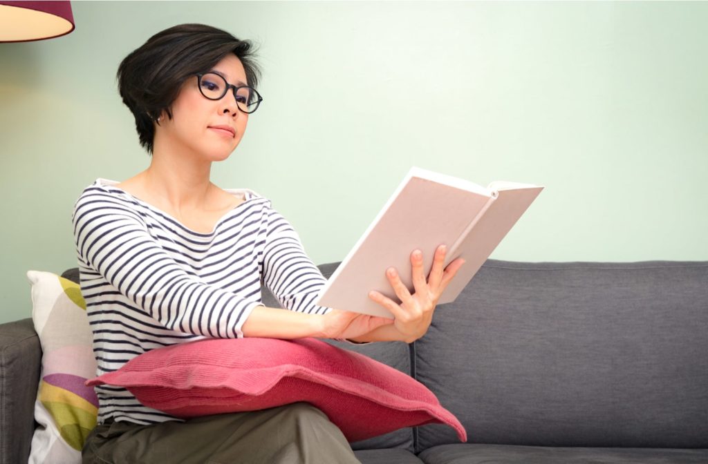 A woman wearing reading glasses and reading a book