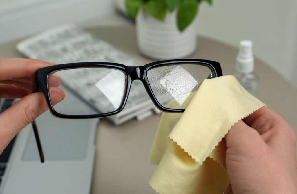 Cleaning spray and a proper cloth being used to wipe and remove the dirt on eyeglasses