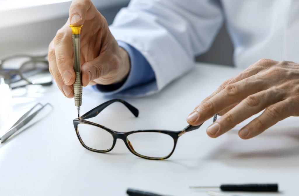 A male optician is tightening the loose arms of an eyeglassses