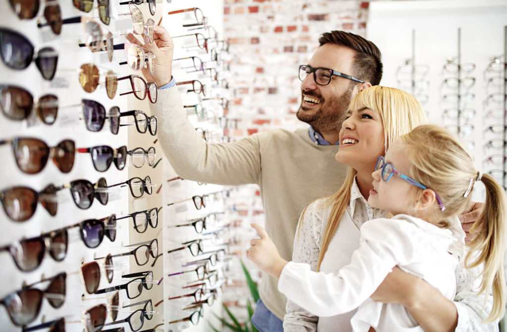 A husband and wife with their daughter are inside an optical shop and looking to buy new eyeglasses that fits well on them.