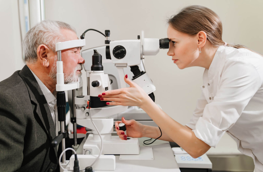 A senior man and his female optometrist performing an eye exam using a medical device to detect eye problems.