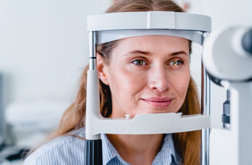 A woman wearing minimal makeup undergoes a slit-lamp examination during her routine eye exam.