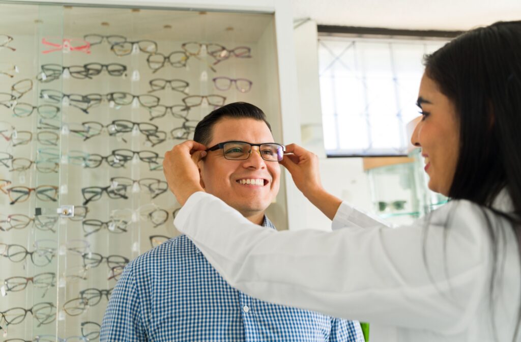 Optician adjusts new eyeglasses on a smiling patient during an eye exam.