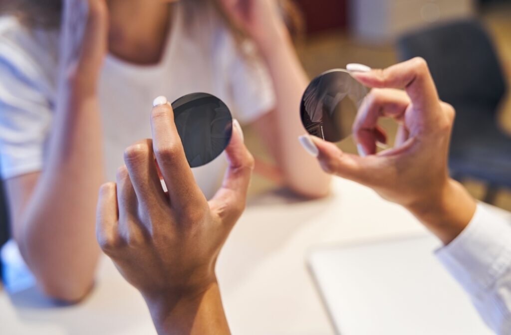 An optician holding prescription sunglass lenses.