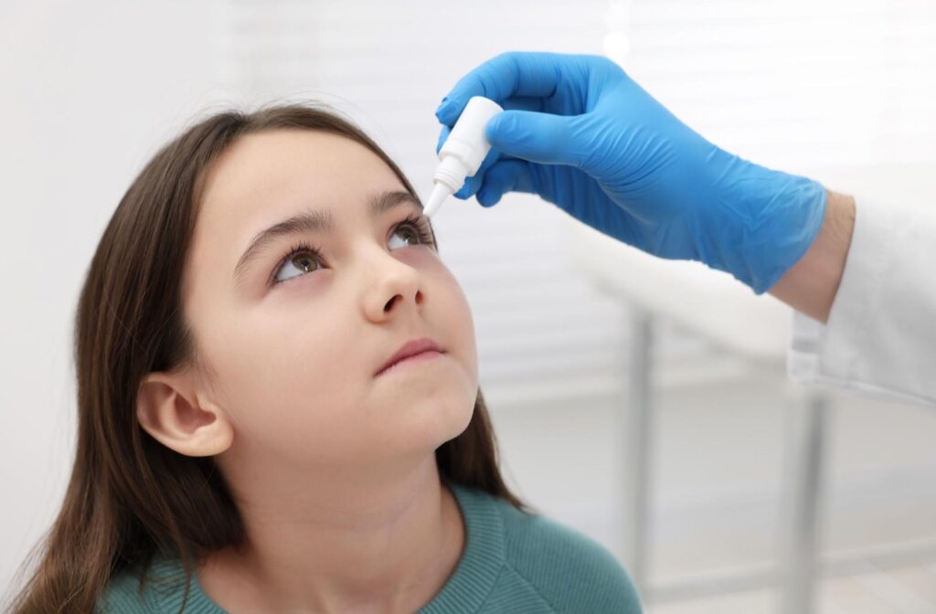 An optometrist inserting atropine eye drops in a child's eye as part of their myopia control treatment.